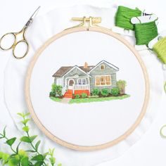 an embroidery kit with scissors and thread on the table next to it is a house