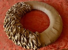 a wreath made out of fabric sitting on top of a red tablecloth with an ornate design