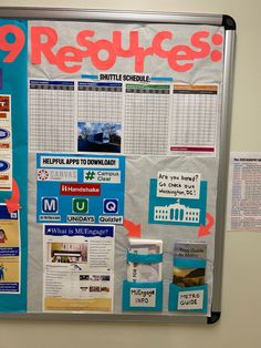 a bulletin board with posters and magnets attached to it's side, in front of a white wall