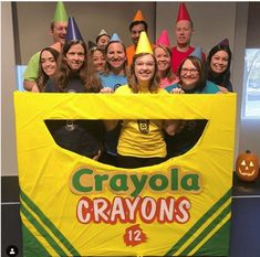 a group of people posing in front of a crayons sign