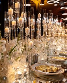 a long table with candles, plates and silverware on it is decorated with white flowers