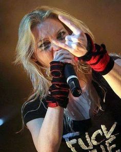 a woman in black shirt holding a microphone and making the vulcan sign with her hand