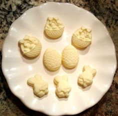 some white chocolates are on a plate with pineapple shaped ones in the middle