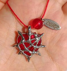 a hand holding a red necklace with silver stars on it and a charm that says years ago