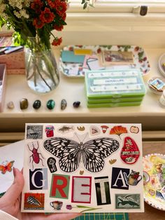 a person holding up a piece of paper with letters and butterflies on it