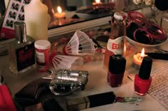 a table topped with lots of different types of nail polishes and candles next to a mirror