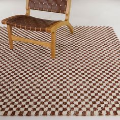 a wooden chair sitting on top of a brown and white checkered rug with no one in it