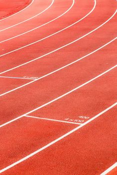 a man running on a red track in the middle of an empty race track with white lines