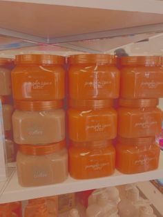 many orange jars are stacked on the shelves in a store, with one being filled with liquid