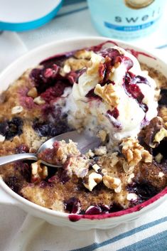 a bowl filled with ice cream and blueberry cobbler on top of a table