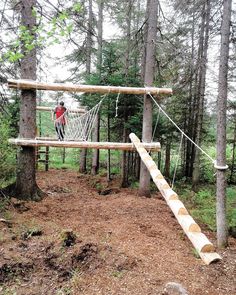 a man walking across a rope bridge in the woods