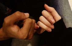 two hands holding each other while sitting on a couch