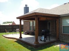 a covered patio with grill and table in the back yard