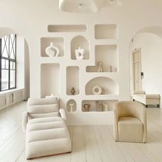 a living room filled with white furniture and lots of bookshelves on the wall