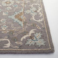 a gray rug with blue and beige flowers on it, laying on the floor in front of a white wall