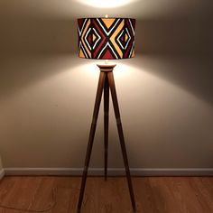 a lamp that is on top of a wooden tripod stand in the corner of a room