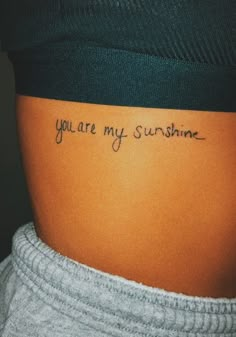 a woman's stomach with the words you are my sunshine written on her lower back