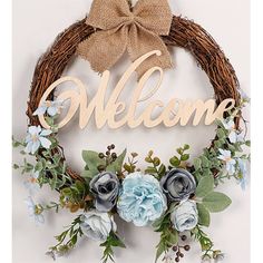 a welcome sign hanging on the side of a wall next to a wreath with flowers