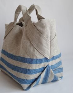 a blue and white striped tote bag on a white background with the handles folded up