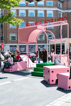 people are sitting and standing around pink benches