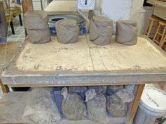 clay pots and bags sitting on top of a wooden table in a room filled with other items