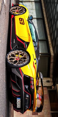 a yellow and black car parked on the side of a building