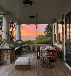 a porch with chairs and a bench on the deck overlooking the ocean at sunset or sunrise