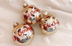 three christmas ornaments with the word omegg painted on them are laying on a white sheet