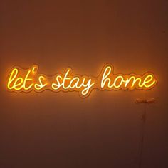 a neon sign that says let's stay home on the side of a wall