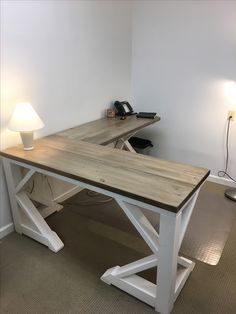 a wooden desk sitting in the corner of a room with a lamp on top of it