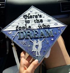 someone holding up a graduation cap that says, there's to the fools who dream