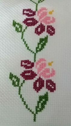 a cross stitch pattern with pink flowers and green leaves on white fabric, which has the word love written across it