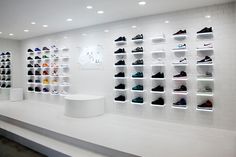 there are many shoes on the wall in this store that is filled with white shelves