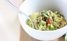 a white bowl filled with pasta and veggies on top of a wooden table