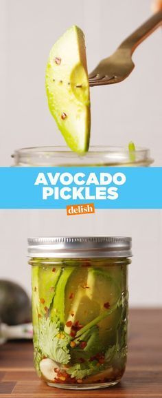 a jar filled with pickles sitting on top of a wooden table next to a spoon