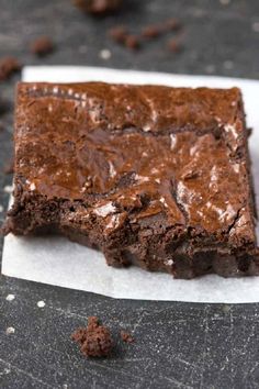 two pieces of brownie sitting on top of a piece of paper next to chocolate chips