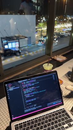 an open laptop computer sitting on top of a table in front of a large window