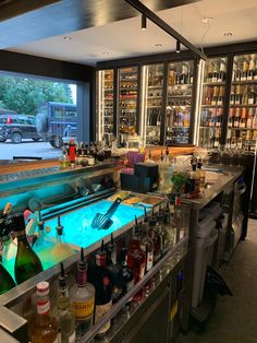 the bar is full of bottles and liquors, including two large windows that look out onto the street