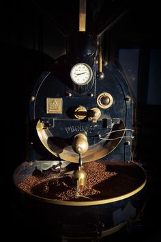 an old fashioned coffee grinder sitting on top of a table with lots of grains