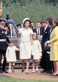 a group of people standing next to each other in front of a car with the queen and prince