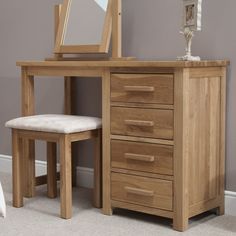 a wooden desk with a mirror and stool next to it in a room that has carpeted flooring