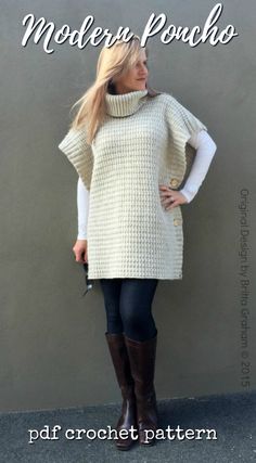 a woman standing in front of a gray wall wearing boots and a white knitted sweater