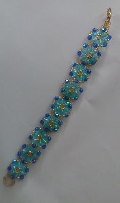 a gold and blue beaded bracelet on a white surface