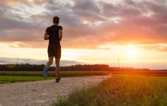 a man running down a dirt road at sunset