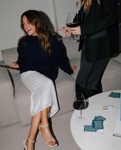 two women standing next to each other with wine glasses in their hands and one holding a tablet