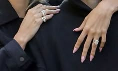 a woman with pink manicures and rings on her hand holding onto another person's arm