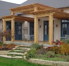 an outdoor patio with steps leading up to the front door and covered in wooden pergols