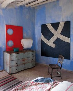 a bedroom with blue walls and furniture in the corner, including a painting on the wall