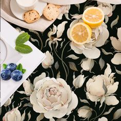 a table topped with blueberries and lemons next to cookies on top of a plate