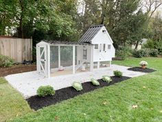 a chicken coop in the middle of a yard with black and white gravel around it